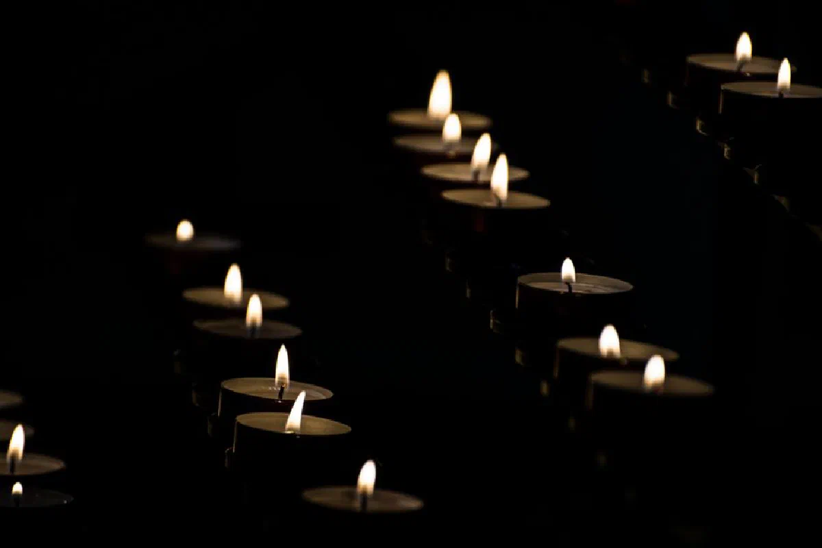 Rows of candles glowing warmly in a dark setting, creating a serene atmosphere.