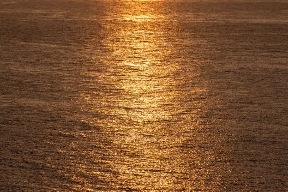 Captivating view of a golden sunset reflecting over calm sea waters, creating a serene atmosphere.