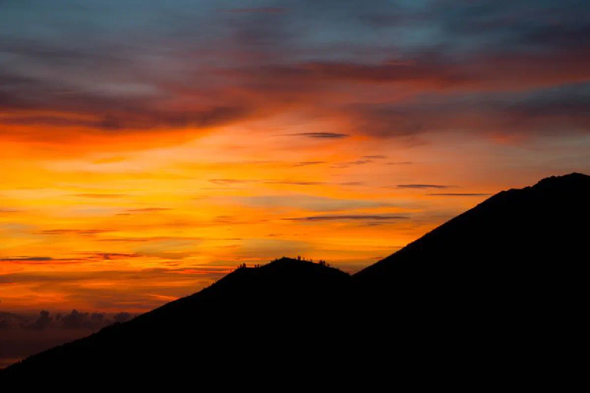 A vibrant sunset illumination over a dark mountain silhouette, perfect for tranquil and natural themes.