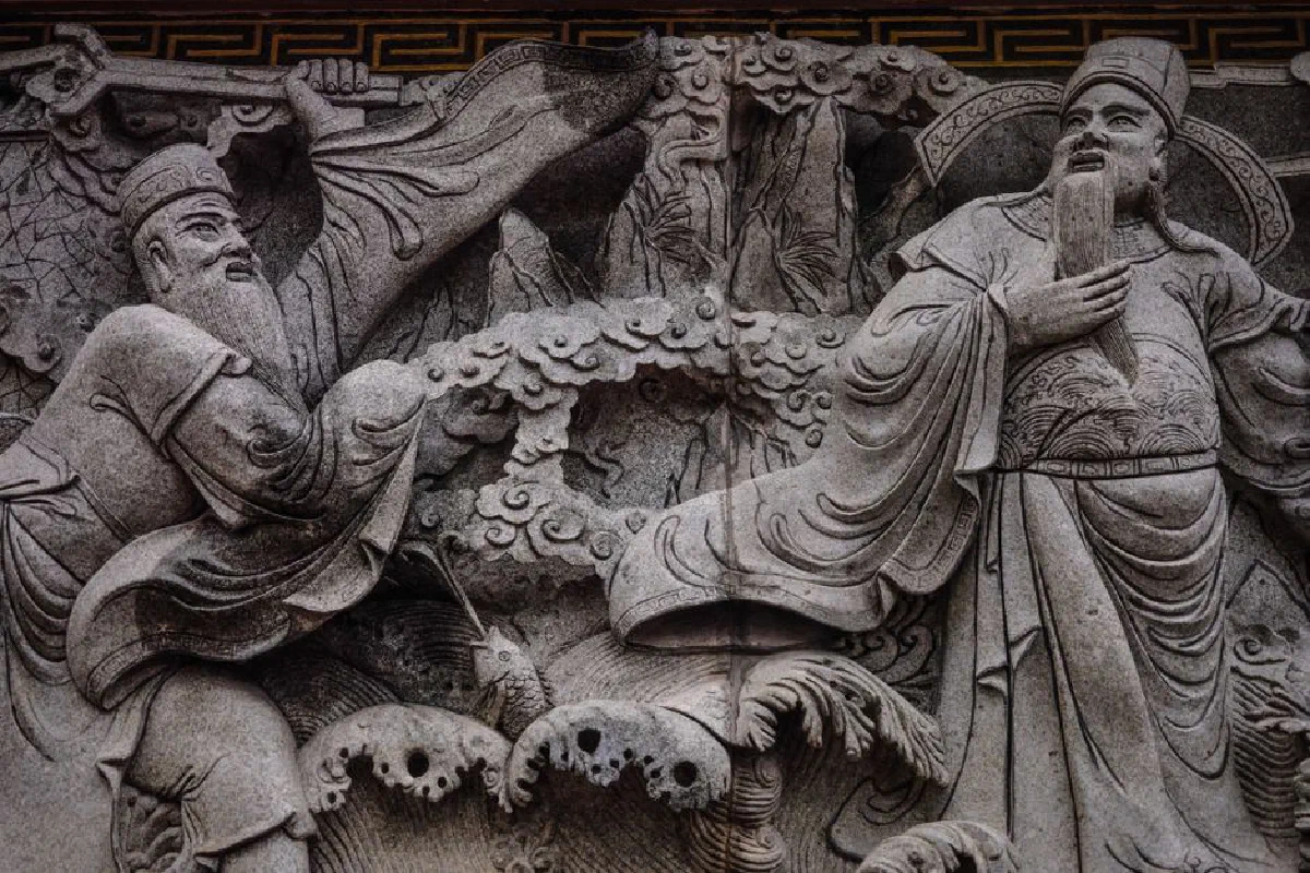 Detailed stone carving depicting ancient oriental figures in traditional attire.
