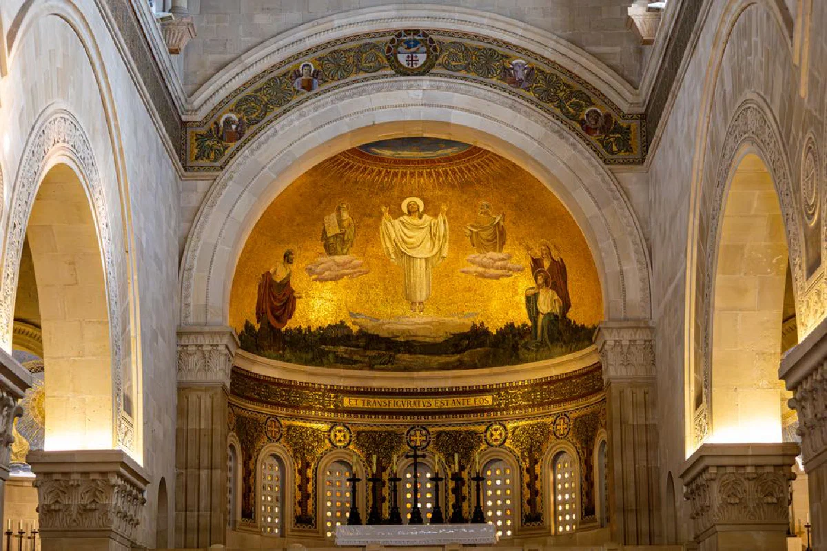 A stunning church interior featuring an intricate religious mosaic under a grand archway.