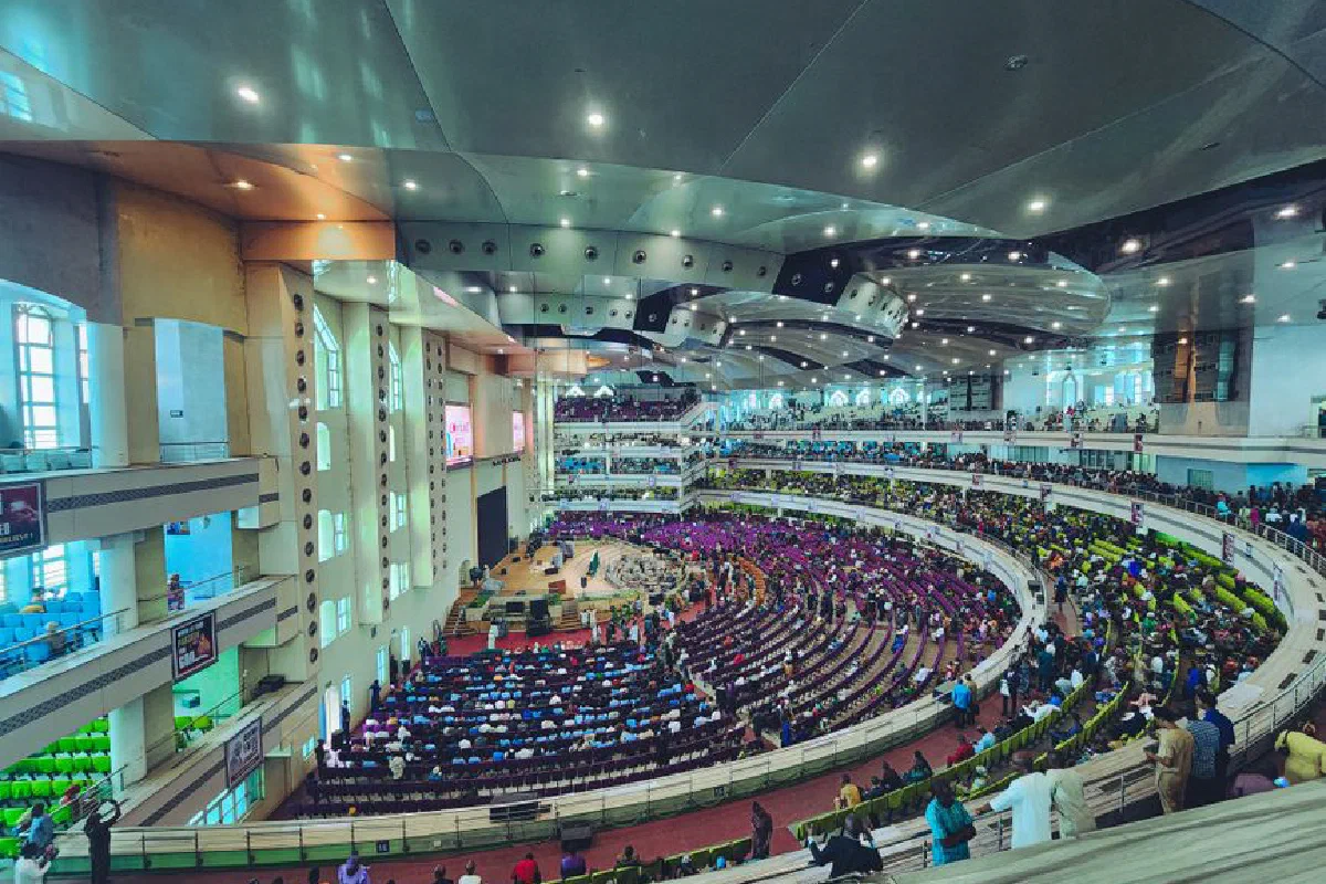 Panoramic view of a spacious indoor auditorium filled with a diverse crowd attending an event.