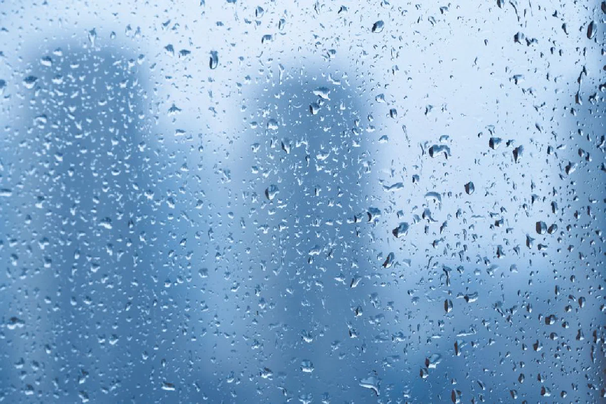 Raindrops on a window with blurred cityscape background creating a tranquil mood.