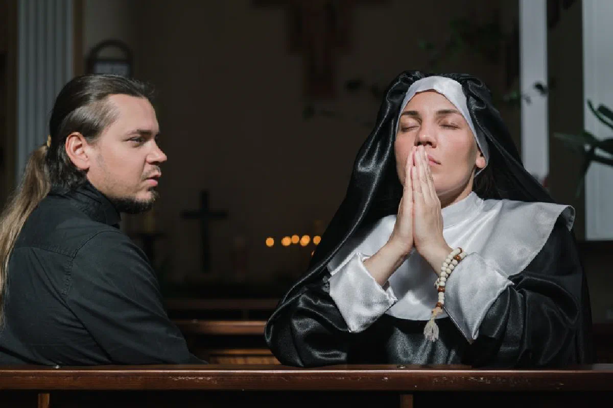 A nun in prayer beside a man in church, depicting faith and devotion.