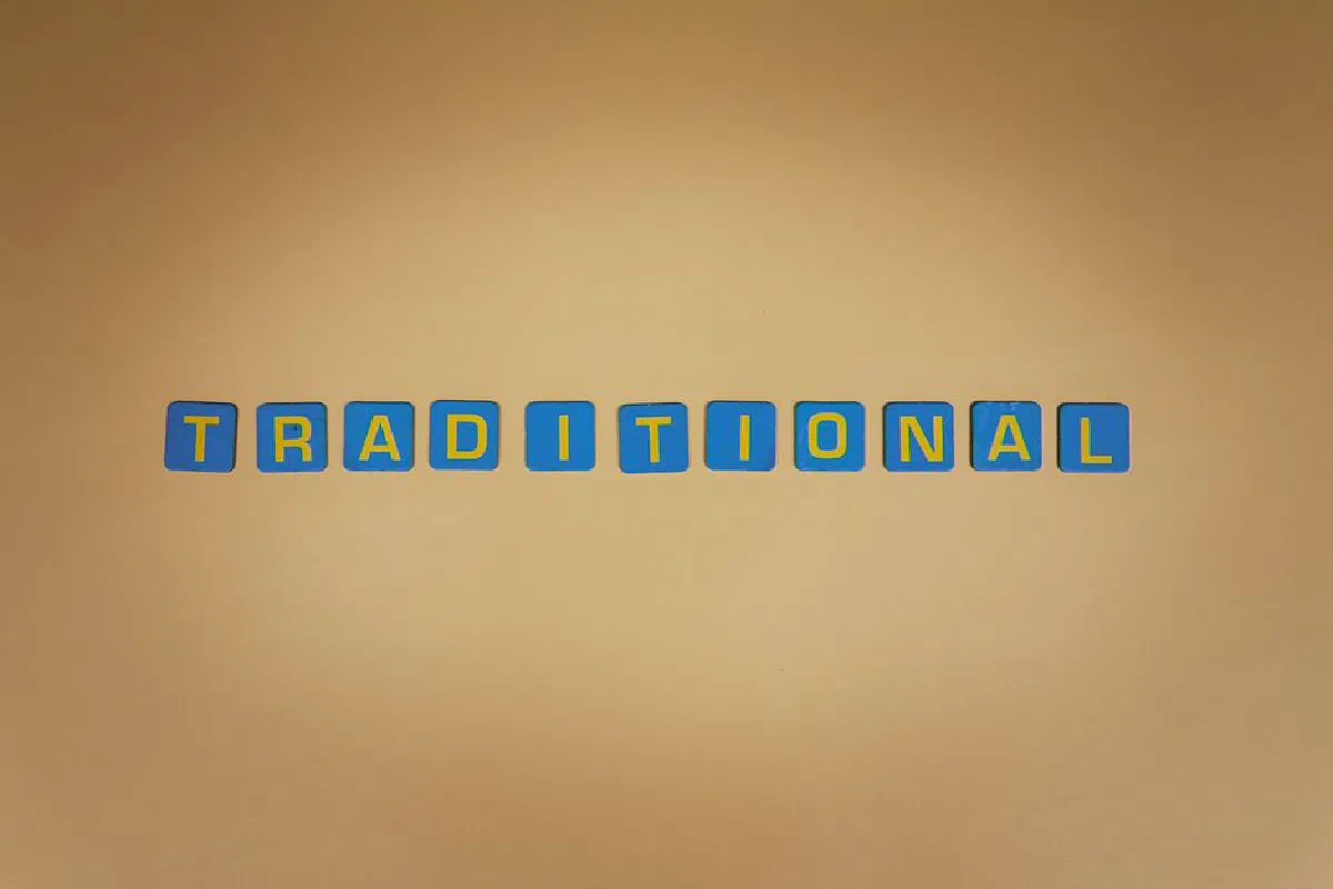 Blue letter tiles spell 'TRADITIONAL' against a warm brown backdrop.