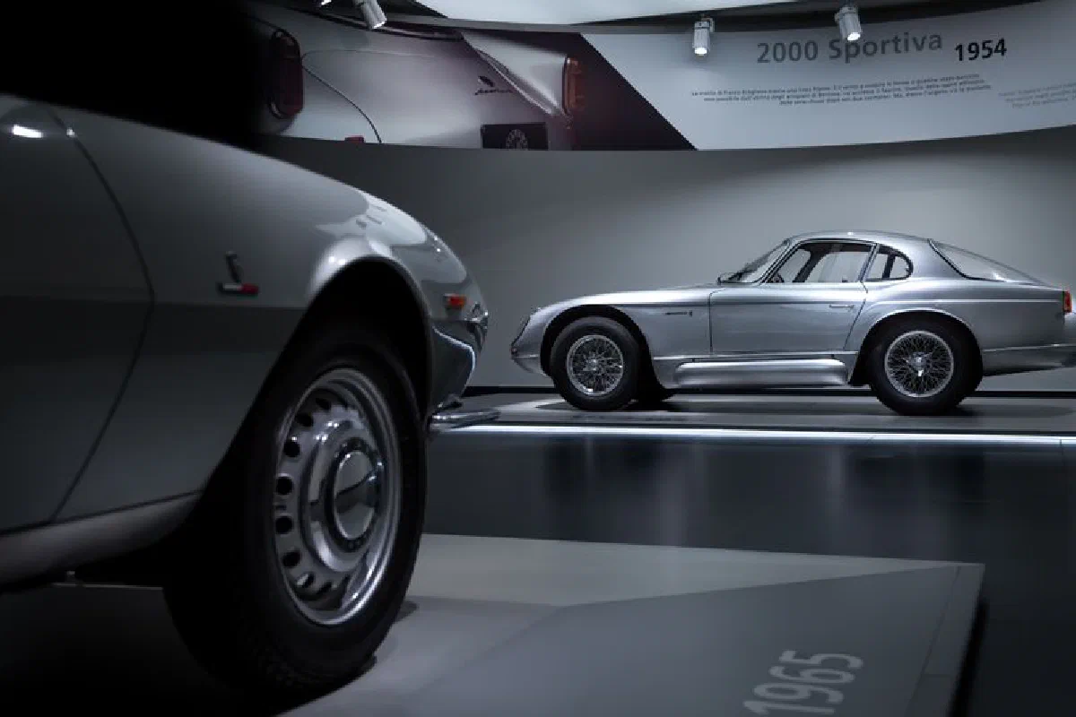 Showcasing a vintage silver classic car inside a museum setting, captured in detail.