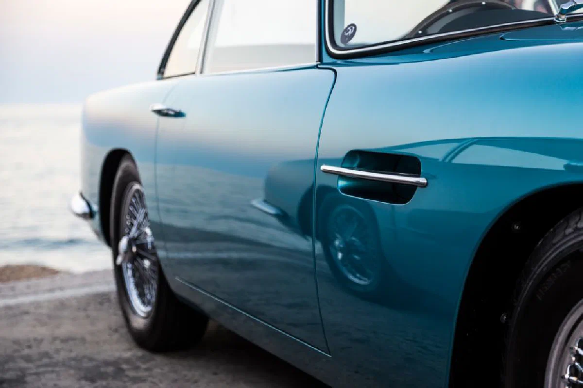 A classic vintage car with polished blue paint near the calm seaside at Marbella, Spain.