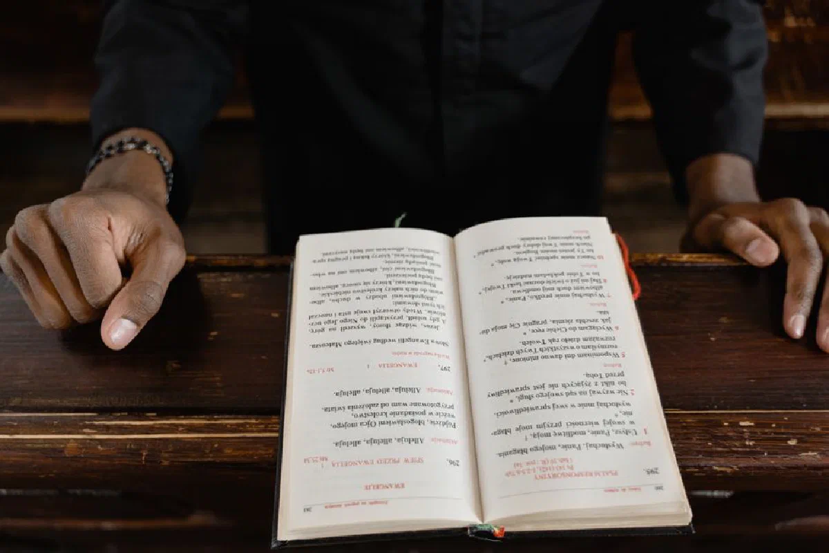 A close-up view of a priest reading an open bible during a church service, focus on hands and book.