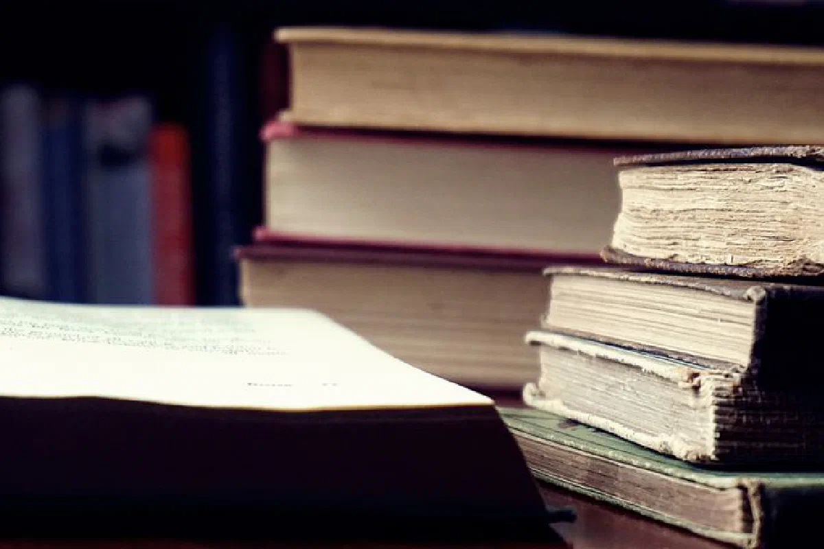 A stack of vintage hardcover books in a dimly lit library setting symbolizes knowledge and wisdom.