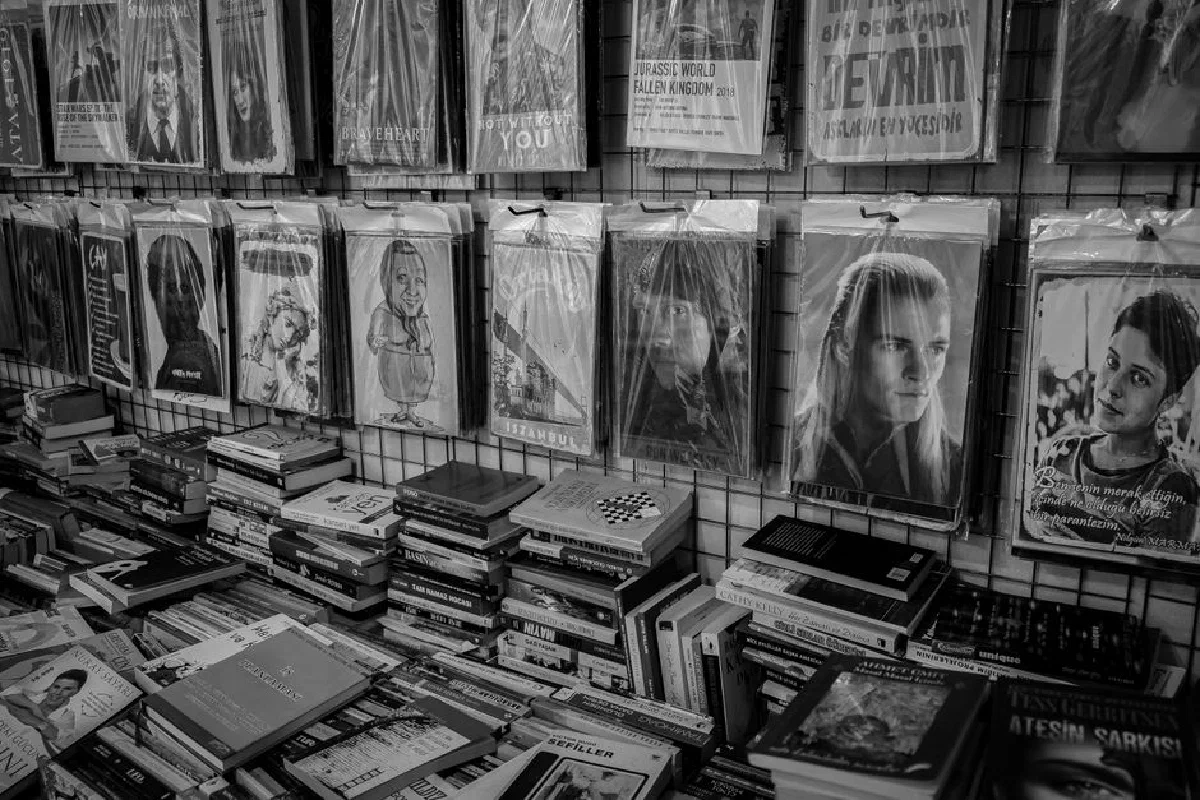 Grayscale image of books and posters in an Istanbul bookstore, offering a vintage feel.