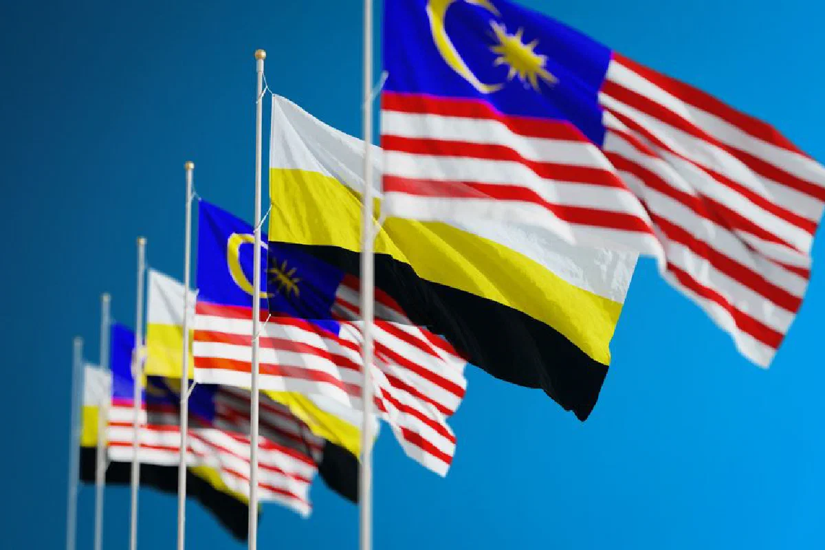 Close-up view of Malaysian and Perak state flags waving in the sky. Bold, patriotic colors stand out.