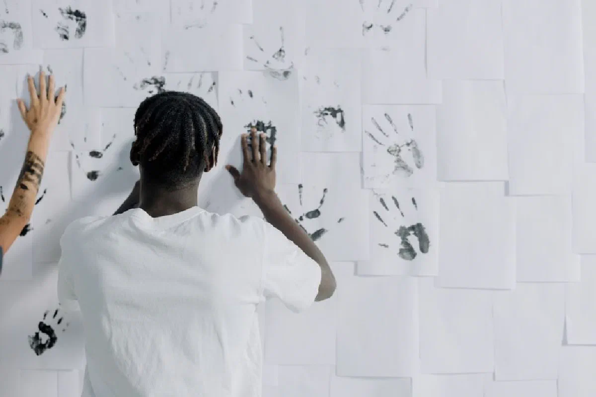 People creating a unique handprint mural on a white sheet wall. Captures artistic expression.