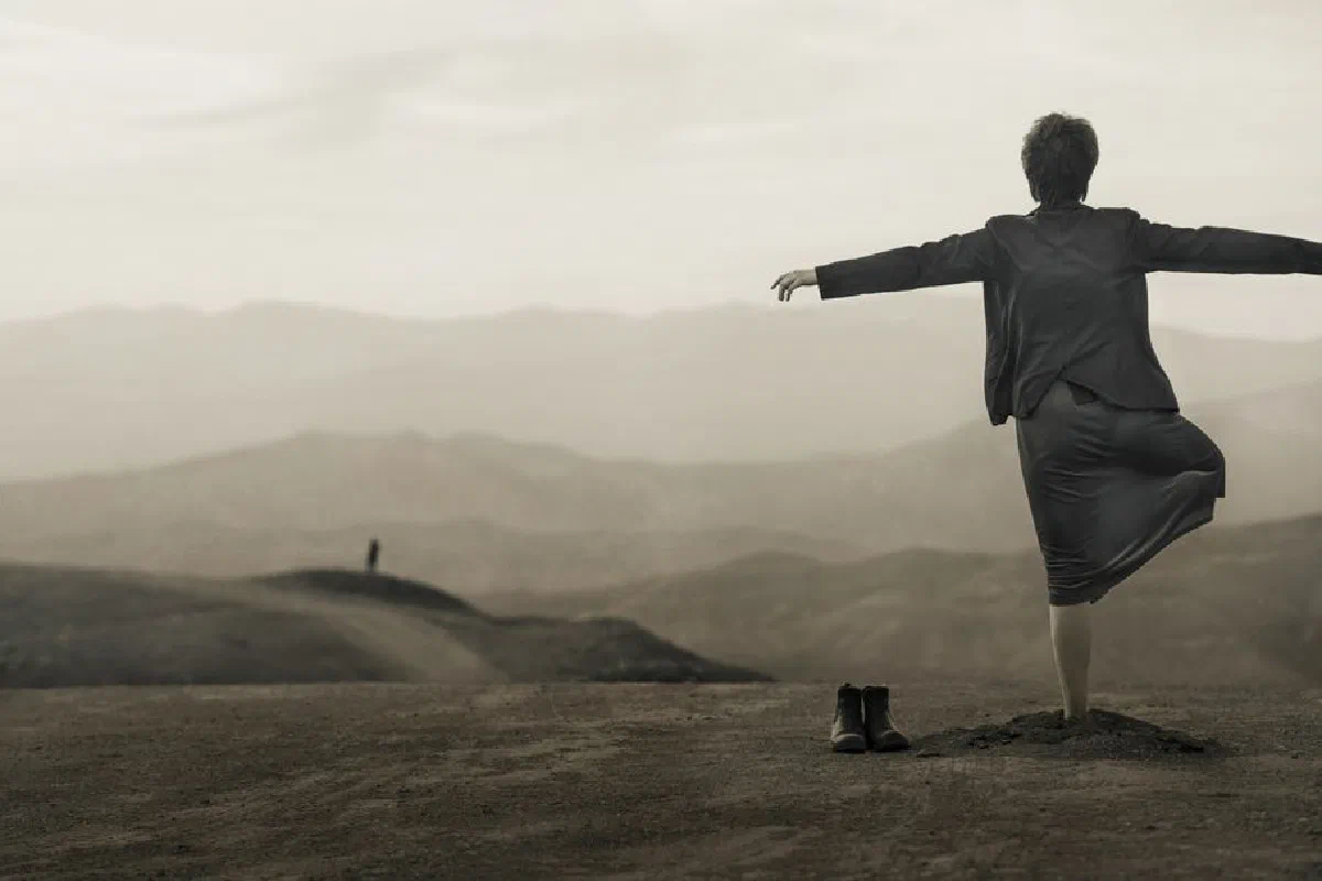 A person stands on a mountain edge embracing freedom in Alborz, Iran.