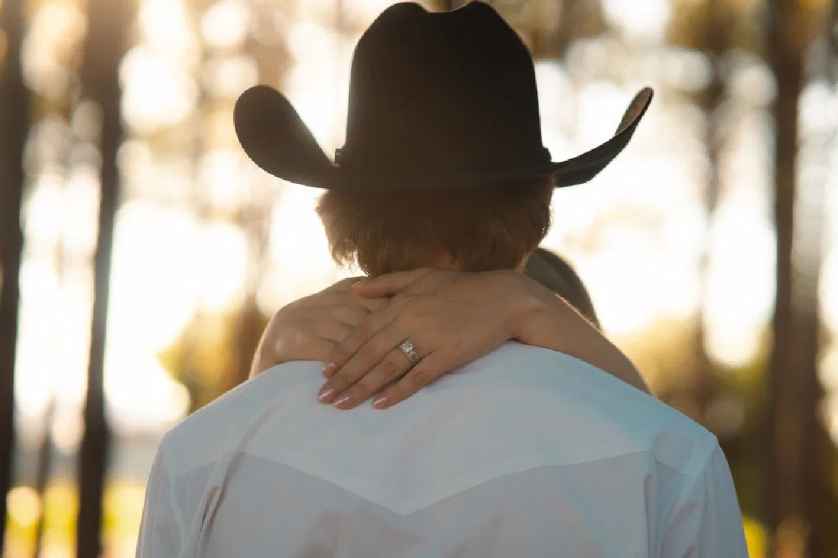 A couple embraces warmly in a sunlit forest, highlighting love and natural beauty.