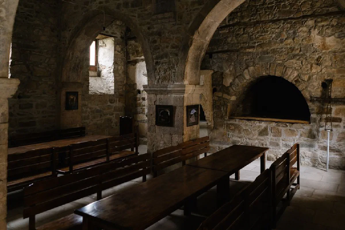 Discover the serene atmosphere of an ancient stone church with empty wooden benches and arches.