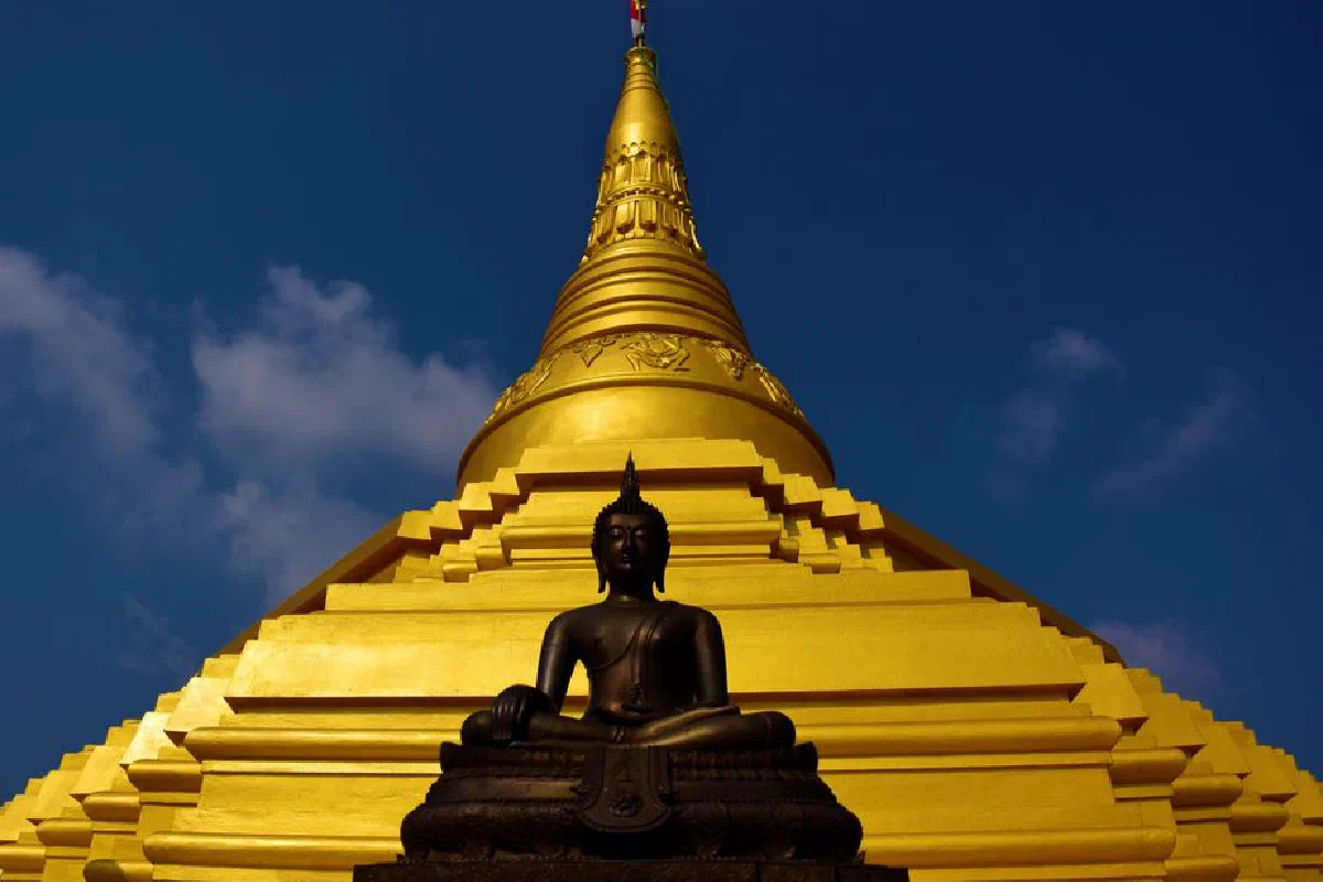 A captivating view of a golden stupa with a Buddha statue in Sri Lanka against a blue sky.