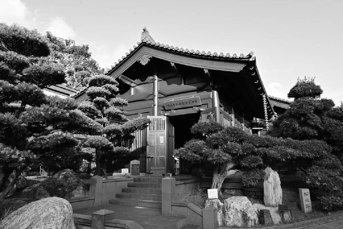 A serene Japanese temple surrounded by trees in a beautiful black and white shot.