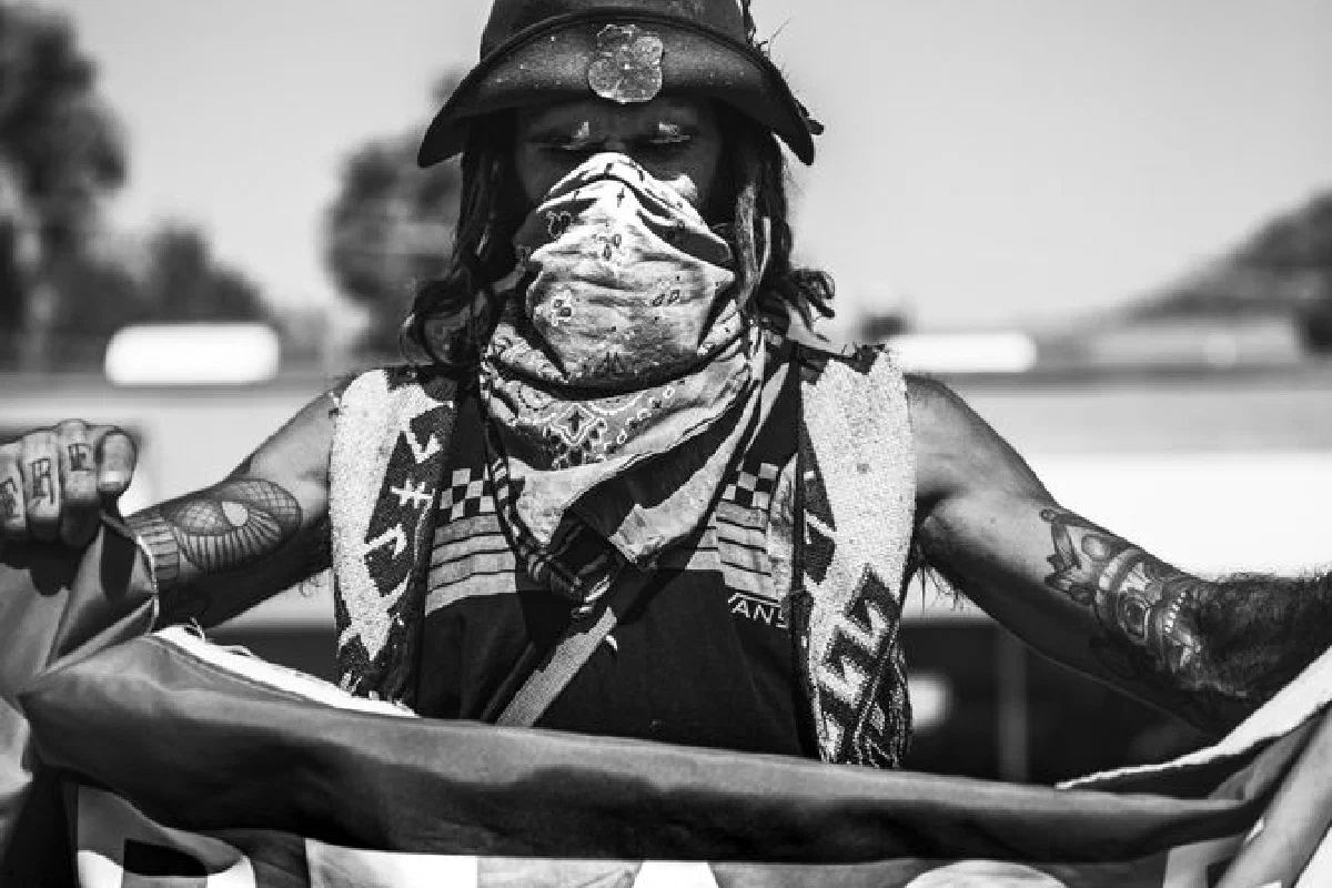 A dramatic black and white portrait showing a protester holding a peace flag.