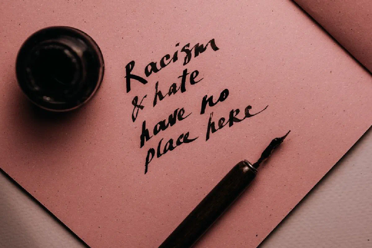 Close-up of handwritten message on pink paper promoting anti-racism and love.