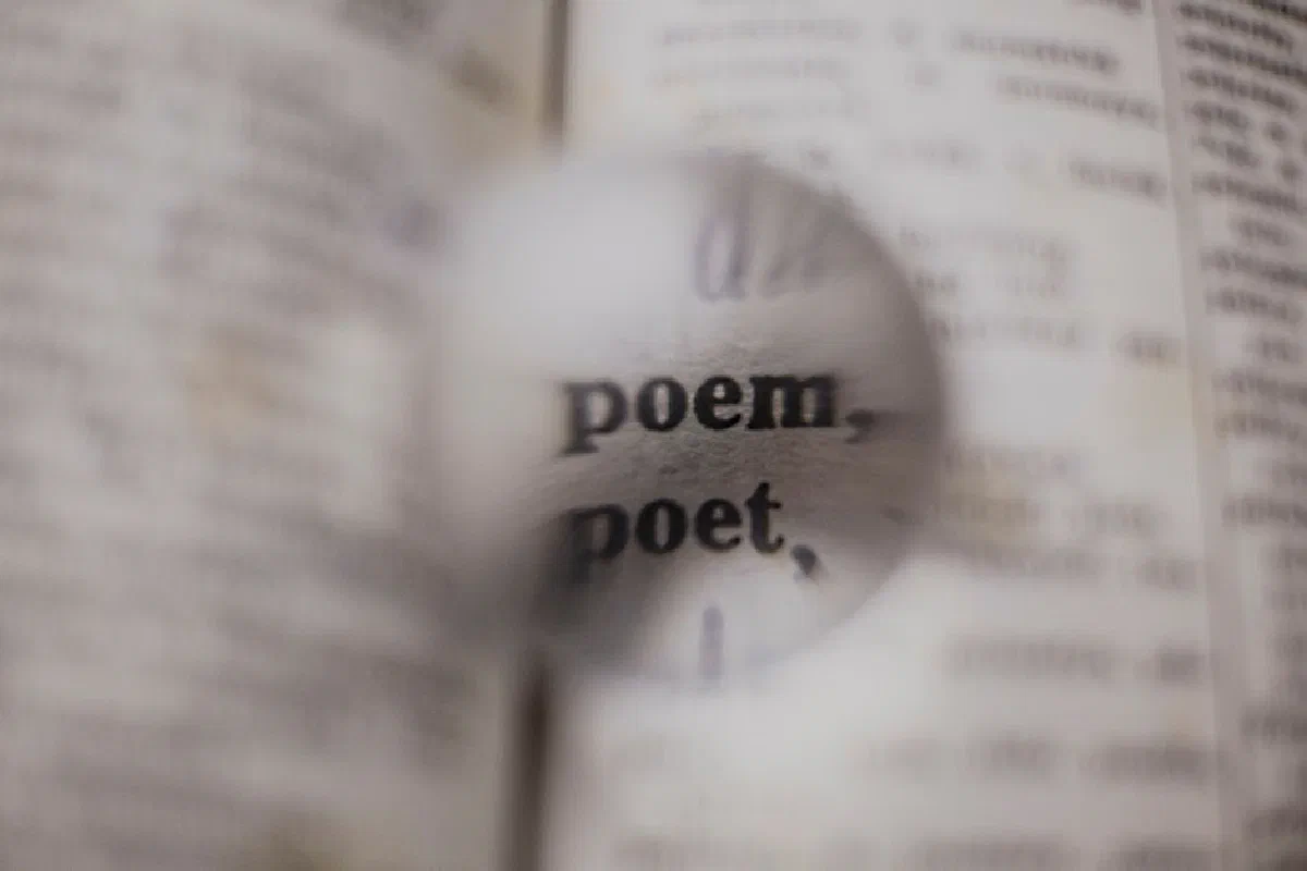 Close-up of words 'poem' and 'poet' magnified in a dictionary