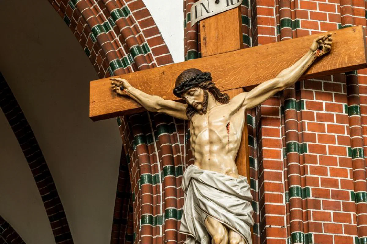 Crucifix sculpture of Jesus on the cross displayed in a brick church interior.