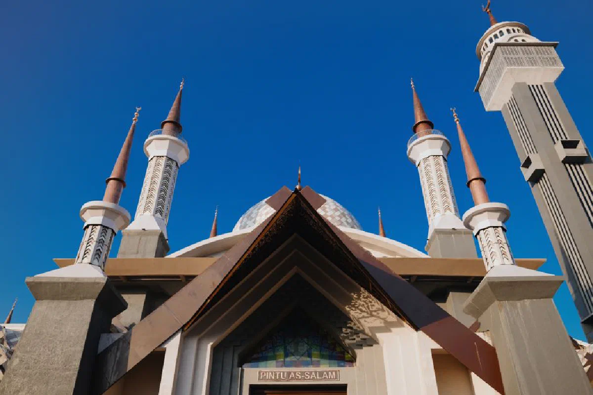 Stunning view of a mosque with tall minarets against a blue sky in Jawa Barat, Indonesia.