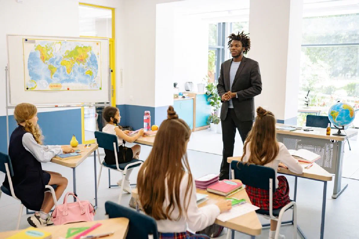 Teacher engaging with students in a bright, modern classroom setting.