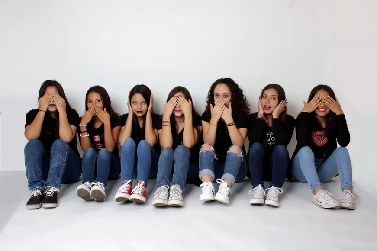 Group of young women posing playfully indoors expressing see no evil, speak no evil, hear no evil theme.