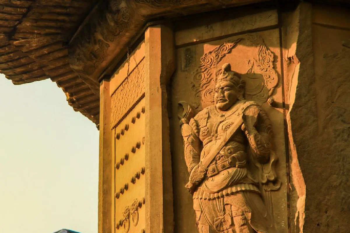Detailed stone carving of a warrior on historic architecture in warm sunlight.
