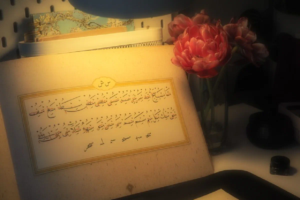 A serene scene of Arabic calligraphy illuminated by soft light with red tulips beside it.