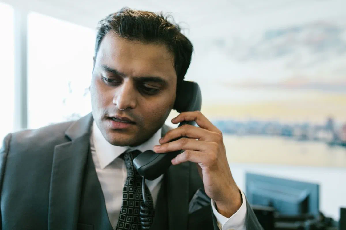 South Asian businessman in a suit making a phone call in a modern office setting.
