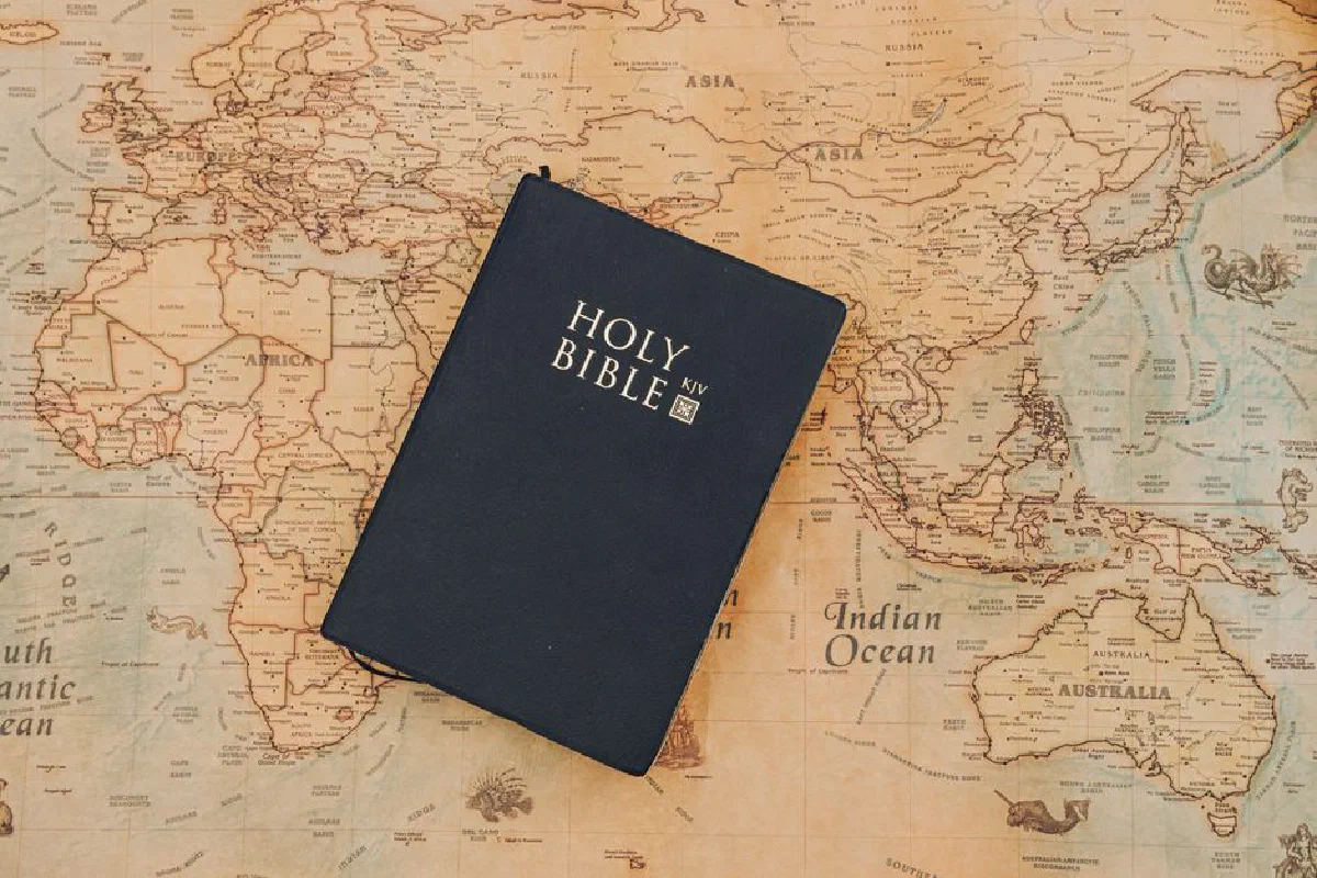 Holy Bible resting on an old-fashioned world map. Inspirational travel and faith concept.