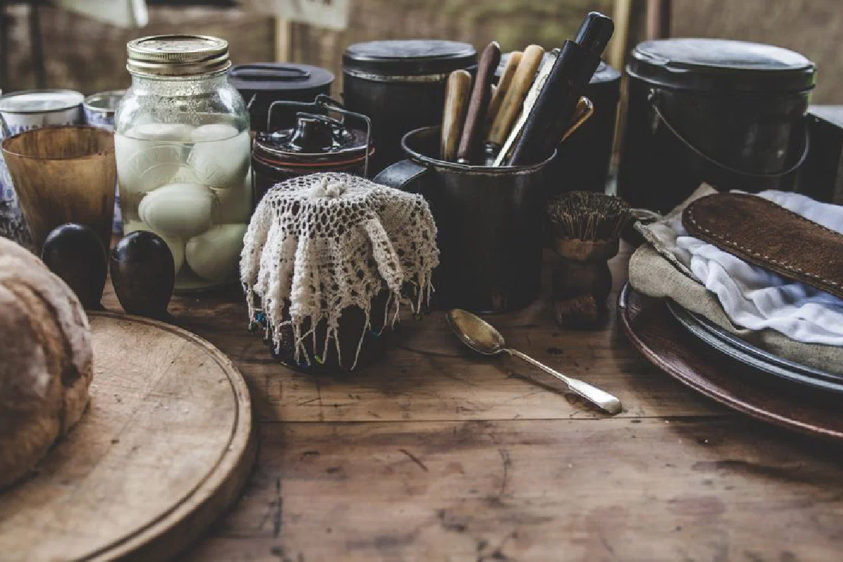 A rustic kitchen scene featuring pickled eggs, bread, and kitchenware on a wooden table.