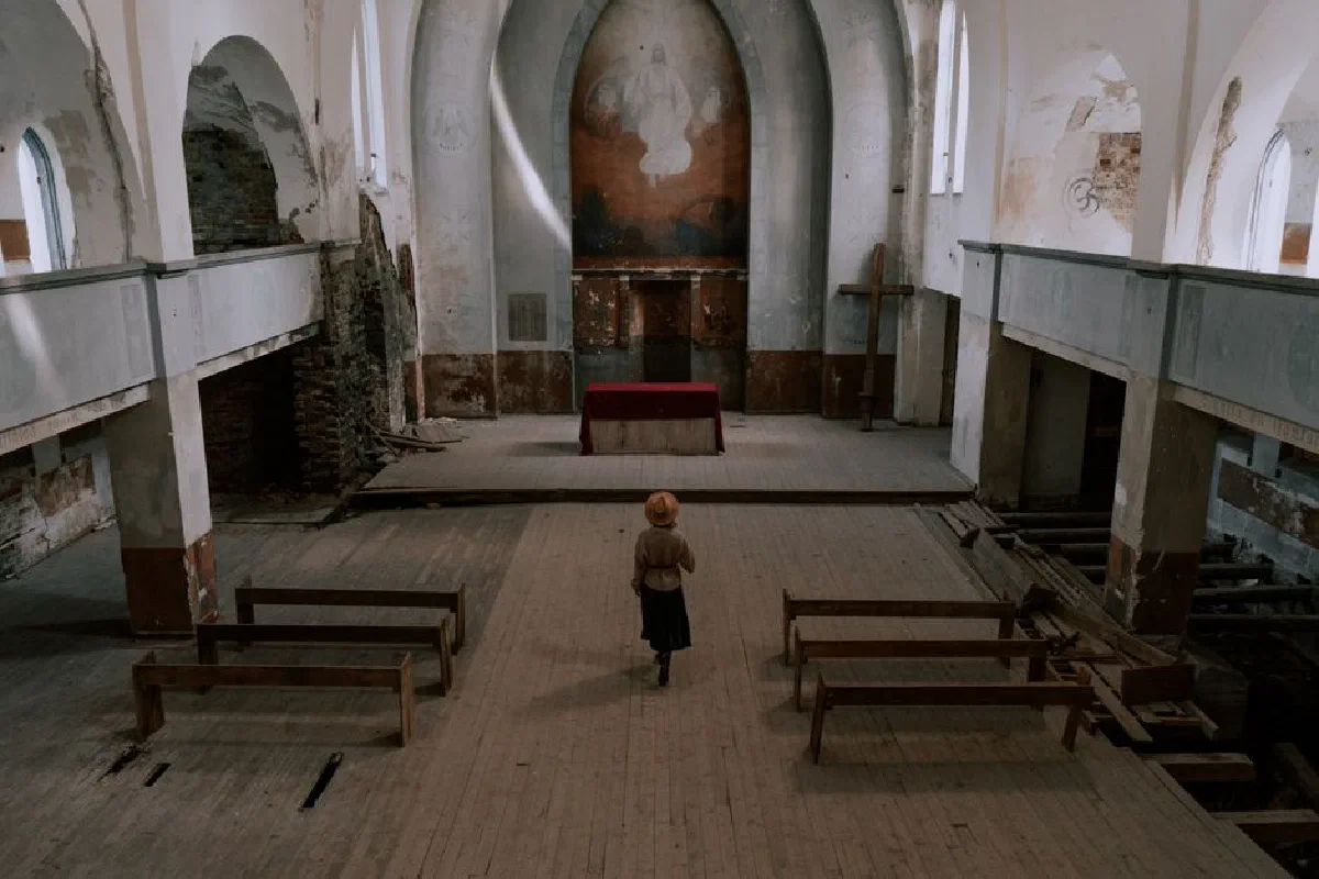 A woman stands in an abandoned church, capturing religious architecture and serenity.