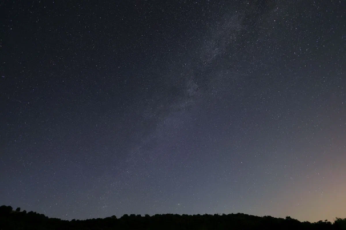 Capture of a starry night in Greece with the Milky Way visible over a silhouetted landscape.