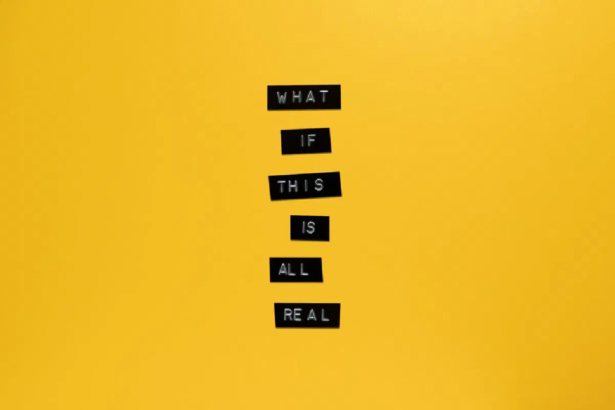Inspirational text 'What if this is all real' on yellow surface.