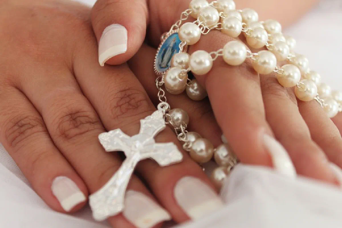 A detailed close-up of hands holding a rosary with a cross, symbolizing faith and prayer.