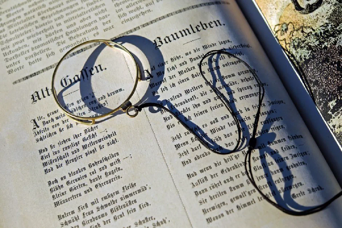 Close-up of vintage magnifying glass on open book, casting a shadow in sunlight.