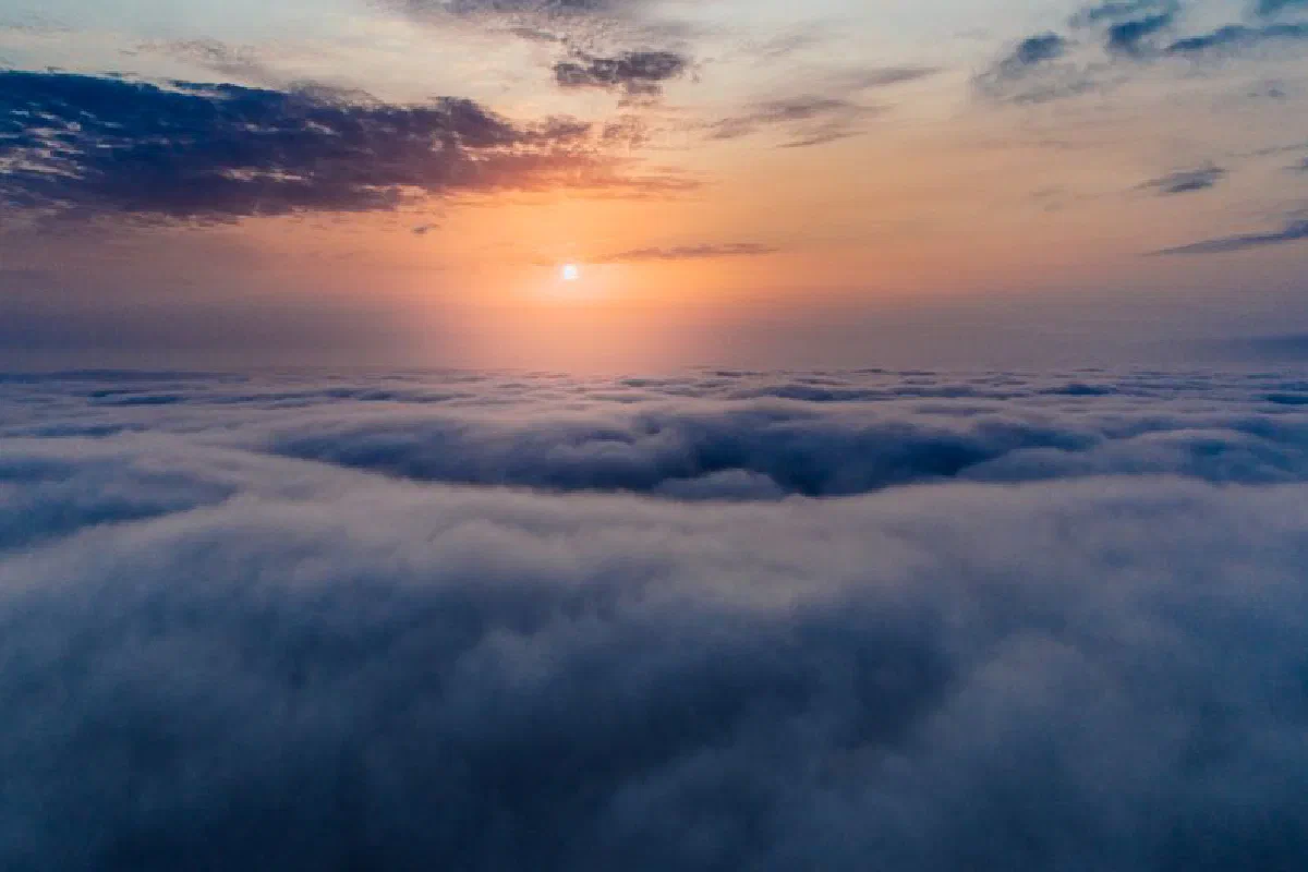 A stunning aerial view of sunrise over a vast cloudscape, capturing serene skies.