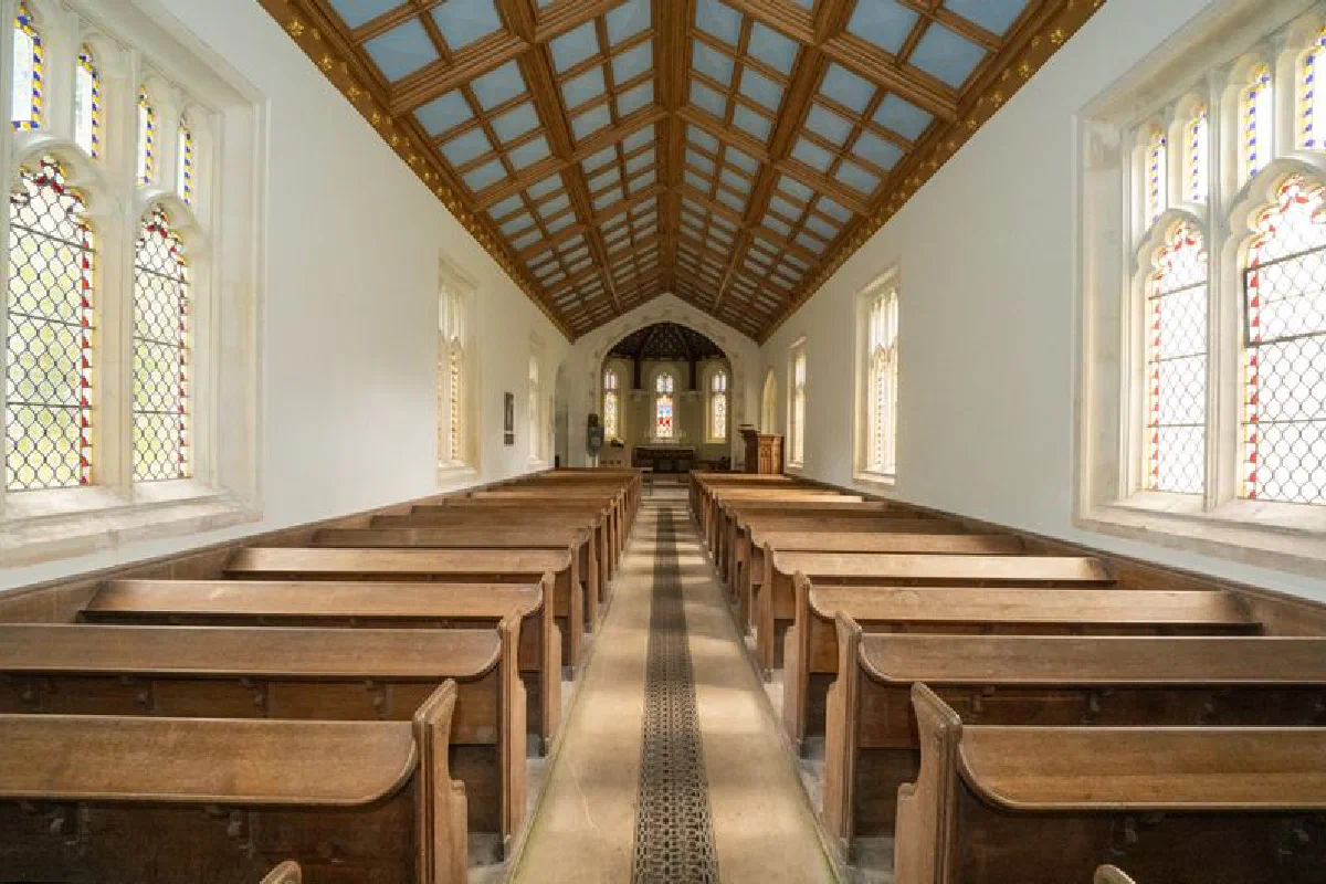 Interior of a traditional church with wooden pews and stained glass windows.