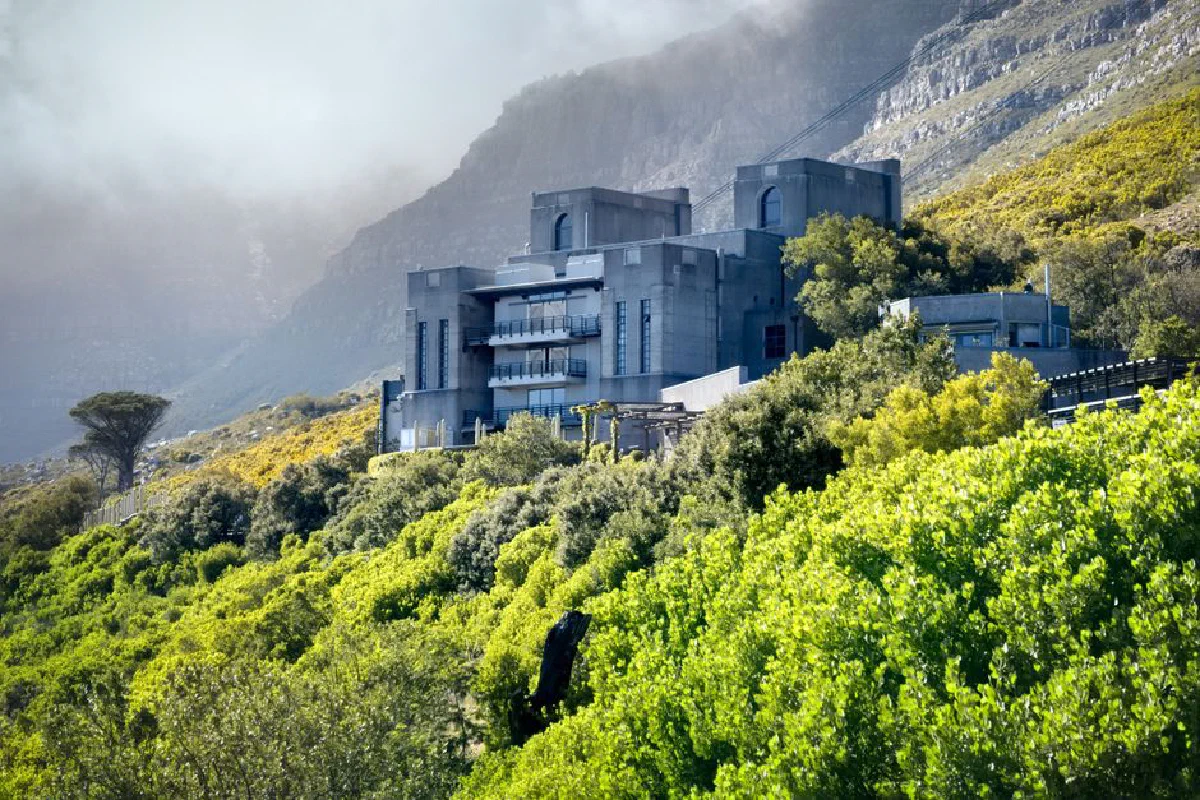 Stunning modern architectural building set against Cape Town's lush mountainside with vibrant greenery.