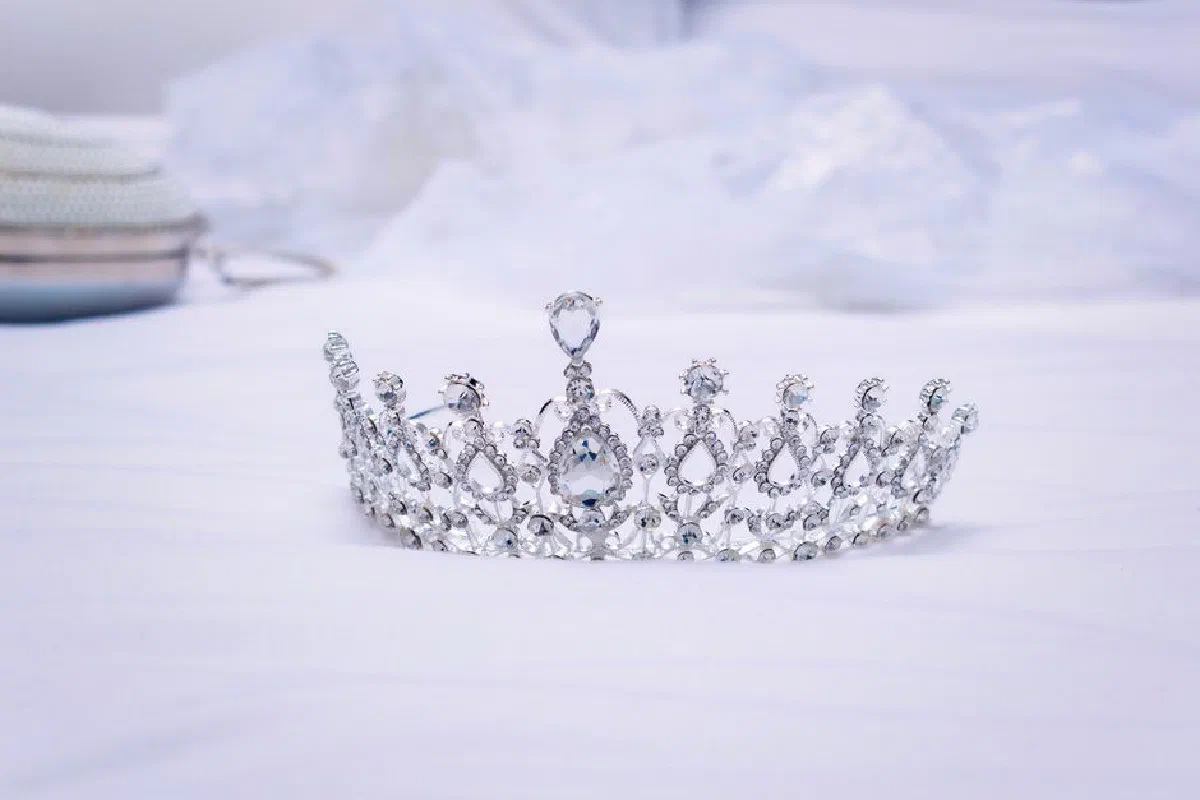 A luxurious diamond-studded crown symbolizing royalty and wealth rests on a serene white backdrop.
