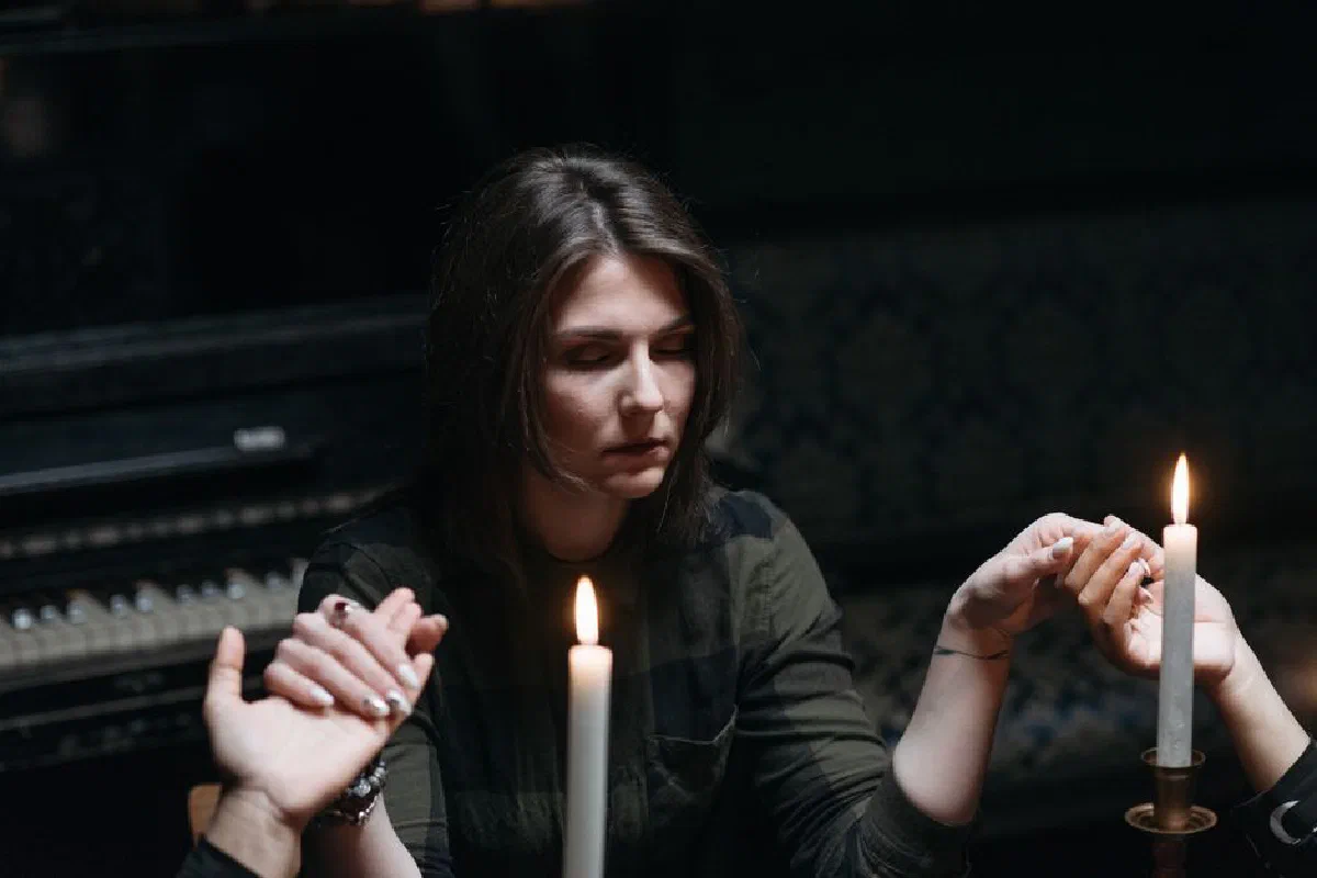 A serene scene of a seance with a woman holding hands and candles, creating a mystical atmosphere.