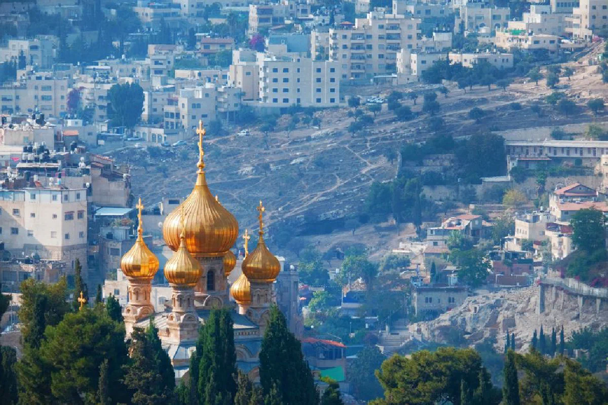 View of the Church of Mary Magdalene's golden domes amidst Jerusalem's urban landscape.