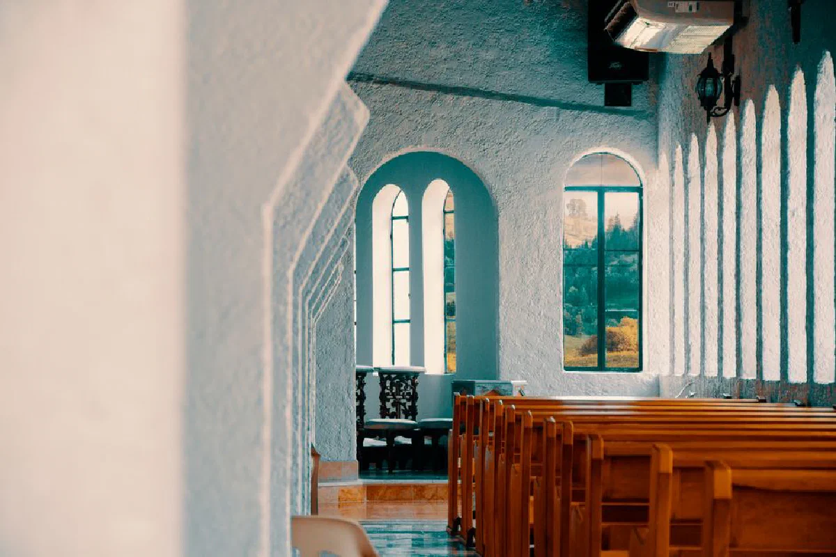 Peaceful church interior in Montería with rows of wooden benches and sunlight streaming through windows.