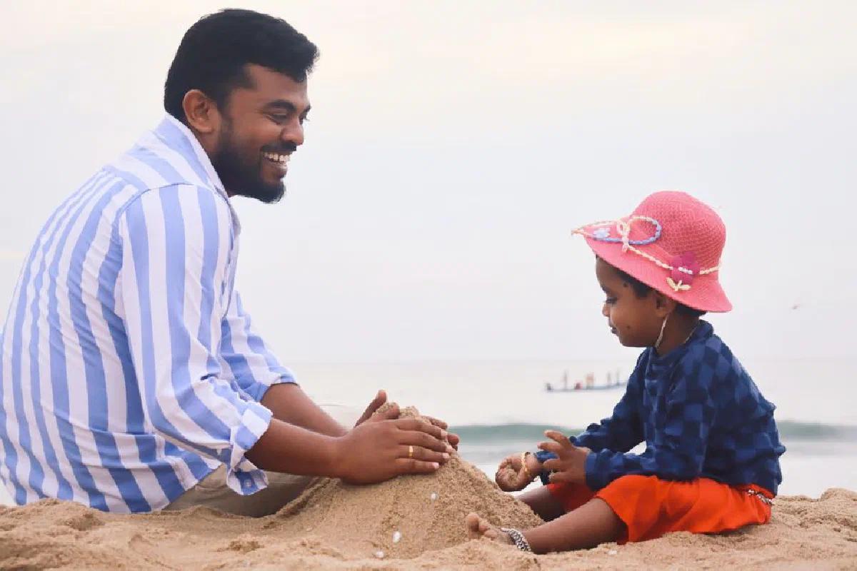 Joyful father and child playing in the sand at the beach, bonding moment.