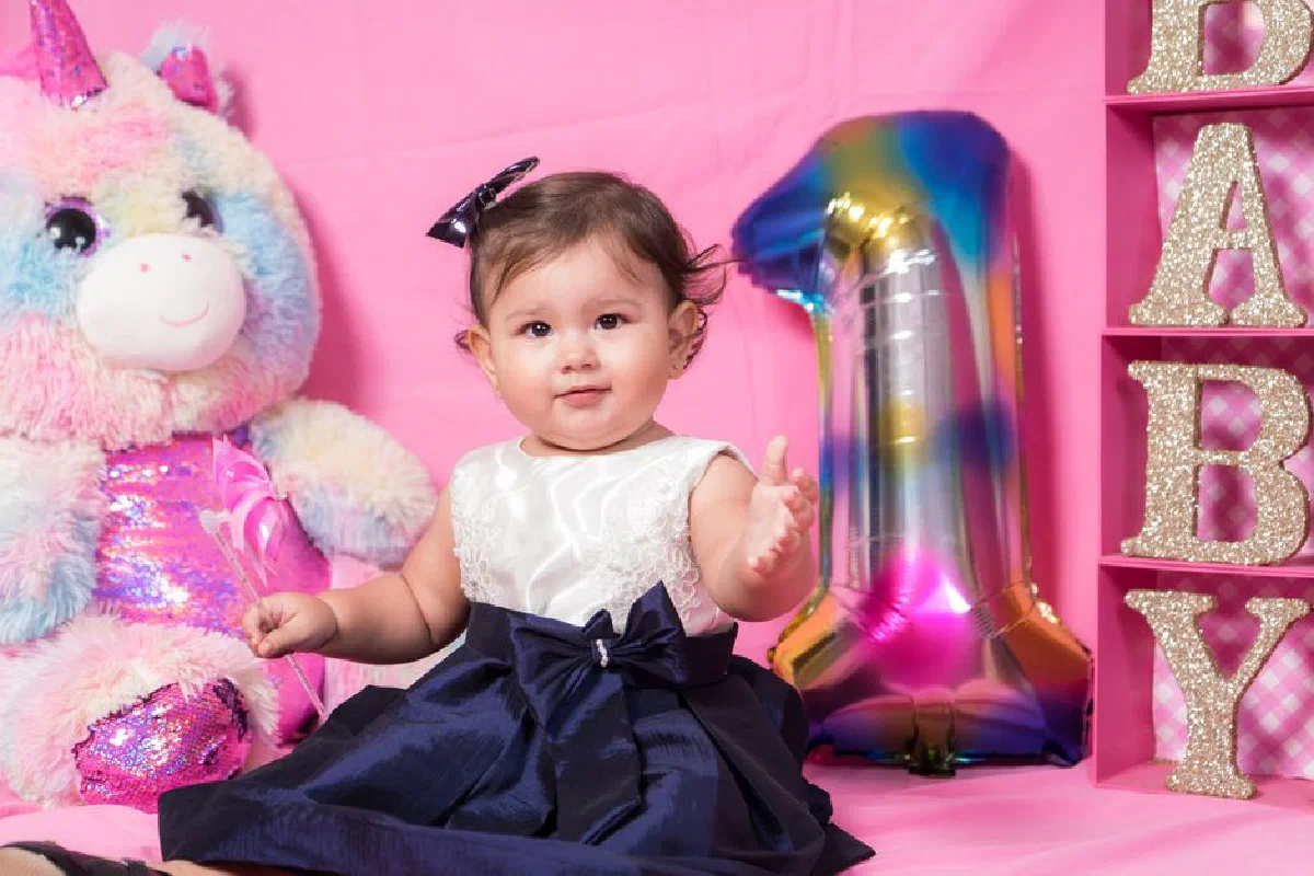 A cute baby in a birthday dress celebrates her first birthday with colorful decorations.
