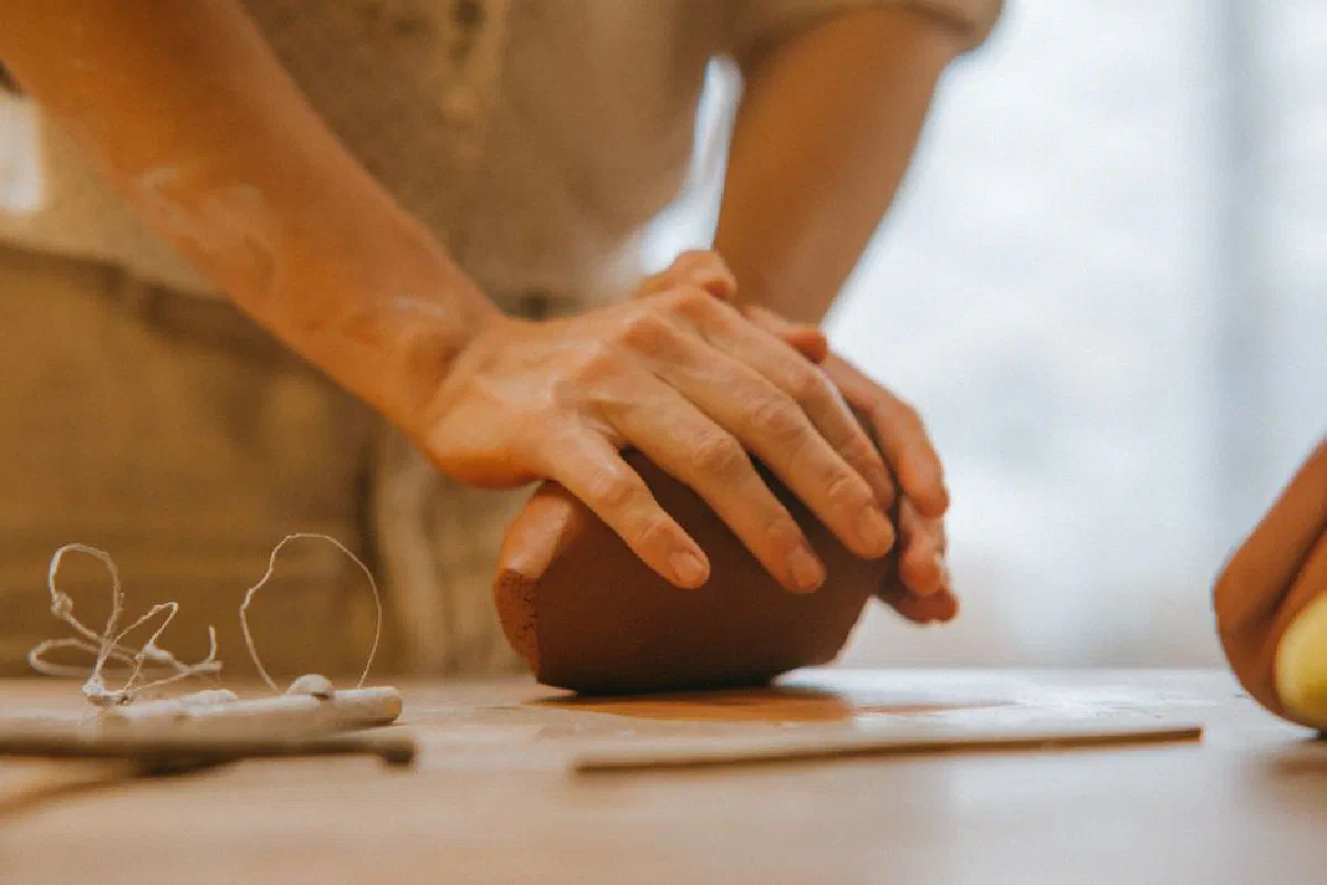 Artisan shaping clay in a close-up view, showcasing handmade craftsmanship.