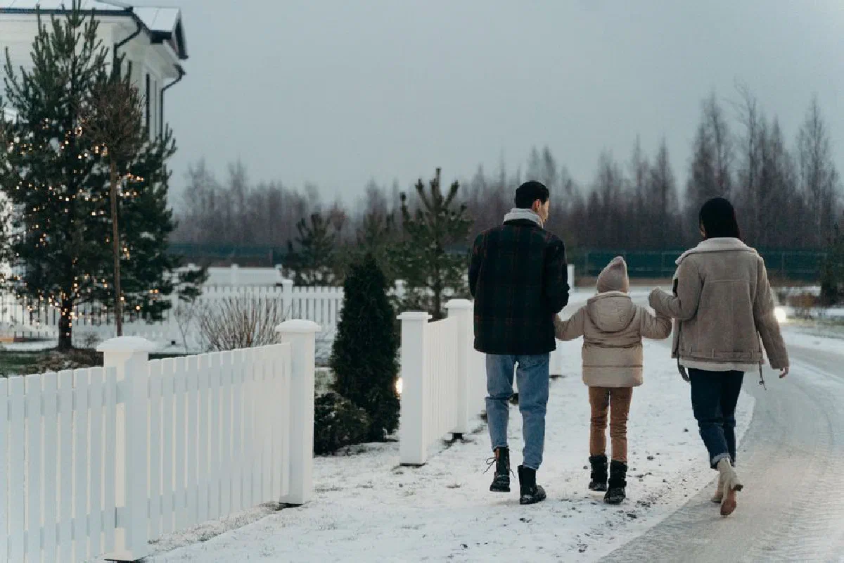 A family walks hand in hand on a snowy day, enjoying the winter outdoors.