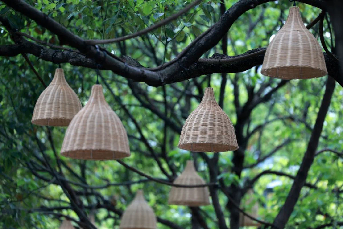 Rustic wicker lanterns hanging from tree branches create an ambient outdoor setting.